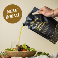 Person pouring black truffle olive oil from a 500ml Kiwi Artisan bag onto a salad.